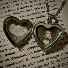 two heart shaped lockes with a man's face inside them on top of an open book