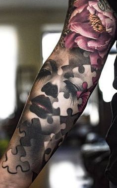 a person with a tattoo on their arm holding a piece of puzzle in his hand