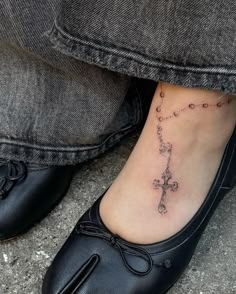 a woman's foot with a cross tattoo on it