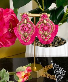 a pair of pink earrings sitting on top of a table next to a potted plant