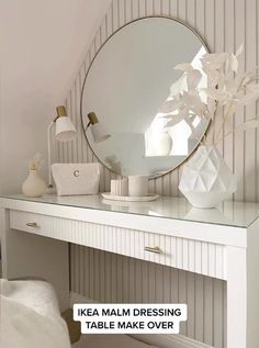 a white desk with a mirror on top of it and a vase next to it