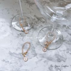 three wine glasses sitting on top of a marble counter next to two gold chain bracelets