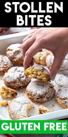 a person picking up some powdered sugar covered doughnuts from a baking pan