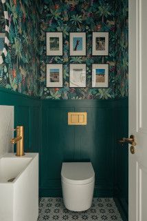 a bathroom with green walls and pictures on the wall above the toilet, along with a sink