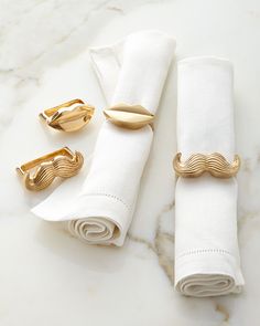 three napkin rings and two napkin holders on a marble countertop with white linens