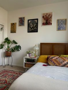 a bed sitting next to a window in a room with pictures on the wall above it