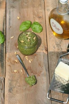 the ingredients to make pesto sauce are displayed on a wooden table with basil leaves