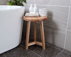 a wooden stool sitting next to a bath tub