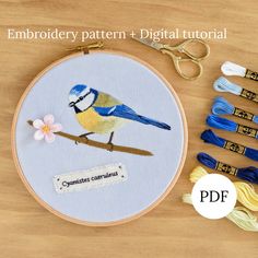 the embroidery pattern is being displayed next to scissors and thread spools on a wooden table