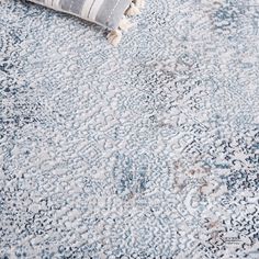 a blue and white rug on the floor with a striped throw pillow next to it