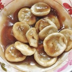 a bowl filled with sliced bananas covered in caramel sauce on top of a table