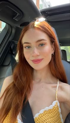 a woman sitting in the back seat of a car wearing a yellow and white top