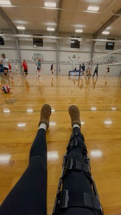 a person with their feet up in the air on a basketball court while others play volleyball