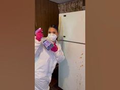 a woman in white coveralls and pink gloves is drinking from a bottle