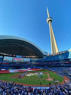 a baseball stadium filled with lots of people and a tall tower in the distance behind it