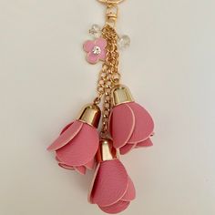 three pink flowers are attached to a gold key chain