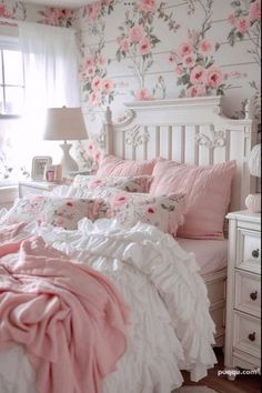 a bedroom with pink and white flowers on the wall, bedding and pillows in it