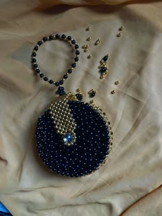 a blue beaded purse and necklace on a white sheet with gold trimmings