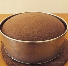 a round cake pan sitting on top of a wooden table next to a brown coaster