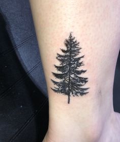 a small pine tree tattoo on the ankle is shown in black and grey ink,