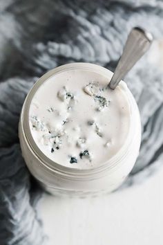 a glass jar filled with white cream on top of a gray and white table cloth