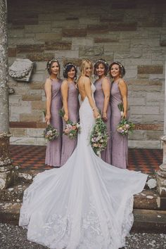 the bride and her bridesmaids pose for a photo in front of an old stone building