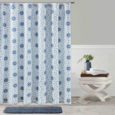 a blue and white shower curtain in a bathroom with a rug on the floor next to it