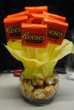 there are many reese candy bars in the glass vase on the table, and one is filled with it's wrappers