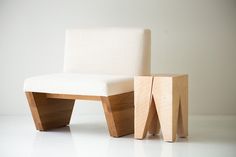 a chair and stool made out of wood on a white floor with a wall in the background