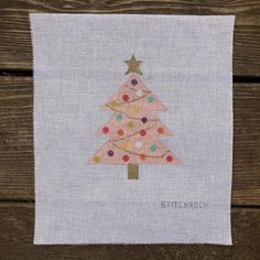 a cross stitch christmas tree on a wooden surface