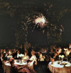 a group of people sitting at tables with fireworks in the background