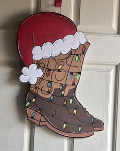 a christmas stocking hanging on the front door with lights and rain boots painted on it