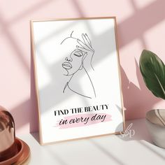 a poster with the words find the beauty in every day on it next to a potted plant