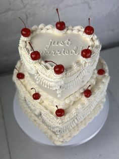 a heart shaped cake with cherries on the top and two tiers in the middle