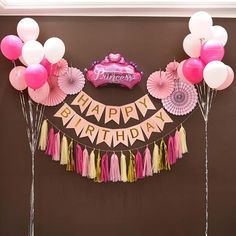 a birthday party with balloons, streamers and tassels on the wall above it