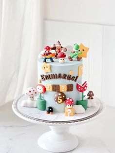 a birthday cake decorated with mario and other toys on a white tableclothed surface