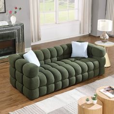 a living room with a green couch and two white pillows on the back of it