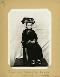 an old black and white photo of a woman sitting on a chair with a hat on her head