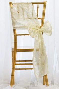 a chair with a bow tied to it's back and sitting in front of sheer curtains