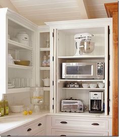 a kitchen with white cupboards filled with appliances