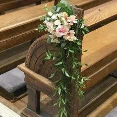 a bouquet of flowers sitting on the back of a wooden bench in front of pews