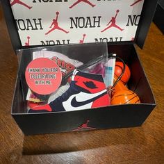 an open box with various items inside on a wooden table next to a pair of sneakers