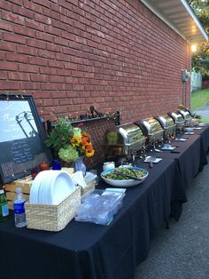 a long table with food on it next to a brick wall in front of a building