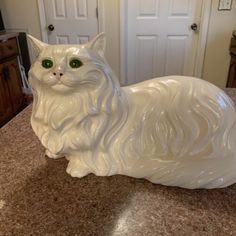 a white cat figurine sitting on top of a counter