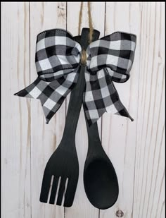 two black and white gingham bows hang from wooden spoons on a wall