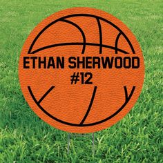 an orange basketball with the number 12 on it is sitting in some green grass,