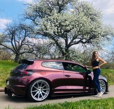 a woman standing next to a purple sports car