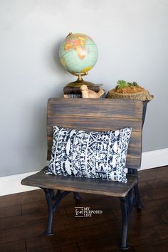 a bench with a pillow on top of it next to a globe and bookshelf