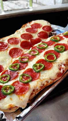 a pepperoni and jalapeno pizza sitting on top of a metal pan