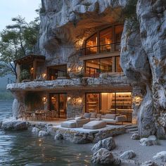 a house built into the side of a cliff next to a body of water at night